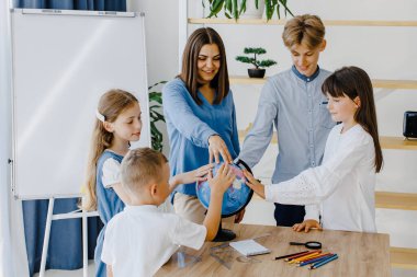 Dünya 'ya dokunuyor. Farklı yaşlarda bir grup çocuk okuldaki geniş bir sınıfta duruyorlar ve öğretmenler dünyaya dokunuyor..