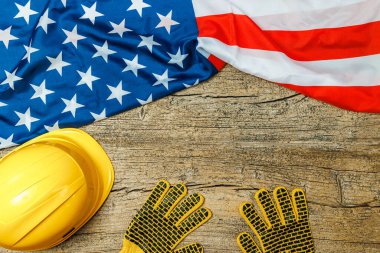 Yellow helmet and gloves with American flag on old wooden table, space for text. Labor day