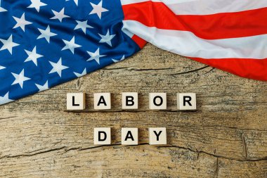 US American flag with wooden cubes with word Labor day on old wooden background. Labor day celebration. 