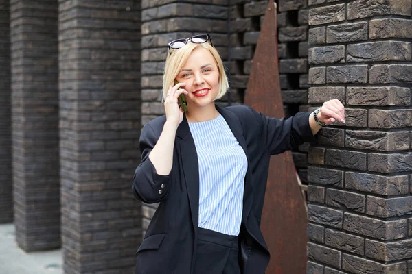 Businesswoman walking across the street talking on smart phone. Happy smiling caucasian busy businesswoman.