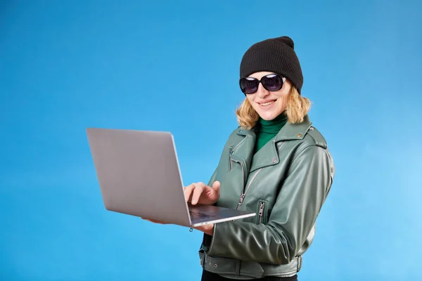 Attractive woman working on new post for her job on laptop, looking at camera with happy inspired smile, watching inspiring video on internet.