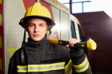 İtfaiyeci arka planında kaskı ve baltası var.. 