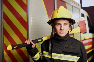 İtfaiyeci arka planında kaskı ve baltası var.. 