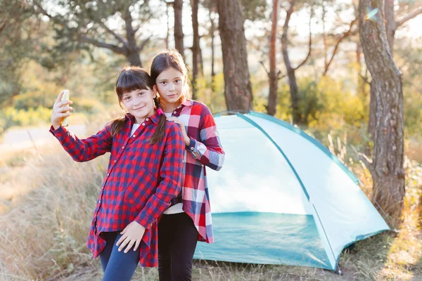 Hadi kampa gidelim. Aile kampı. Hedefe ulaş. Çam ormanının ortasında telefon ekranına bakarak selfie çeken neşeli genç kızlar. Açık hava macerası..