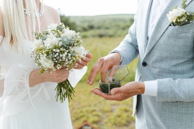 Close-up of the bride giving her hand to the groom to put on her ring during the wedding ceremony. Married life and happy family concept.