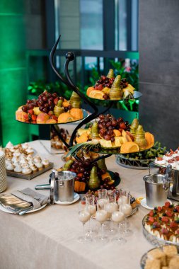 Düğün için. Çikolata. Açık büfe masasında bardaklar, içecekler, meyveler ve farklı tatlılar var..
