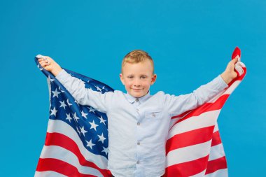 Stüdyoda mavi arka planda Amerikan bayrağı tutan sevimli çocuk. Ülkeye karşı vatanseverlik kavramı