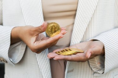El ele tutuşan altın bitcoin, reklam parası, kripto para, dijital para, elektronik yatırım için kopya alanı. Bitcoin tutan iş kadınının kesilmiş portresi ve bunu kameraya gösteriyor. Satış ve iş konsepti