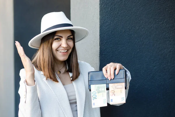 A picture of a happy pretty woman with a wallet with euro banknotes