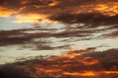 Dönen akşam bulutları batan güneşle aydınlanıyor.