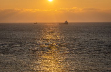 Hollanda açıklarında Kuzey Denizi 'ndeki gemilerin siluetleri renkli günbatımında
