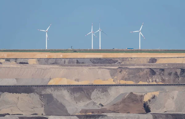 Landscape of Garzweiler brown coal mine in Germany, view of open mine pit with conveyor belts and wind turbines in the background