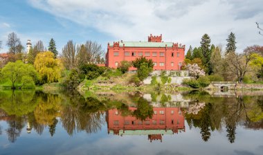 Red, Neo-Gothic castle in Klasterec nad Ohri, Czech Republic, reflected in the river