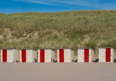 Little cabins in front of high sand dune at dutch beach nearby the village of Schoorl