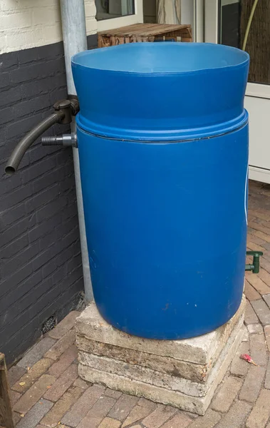 Rain barrel for rain water collection in process of installation, rainwater tank ready to be connected to the gutter