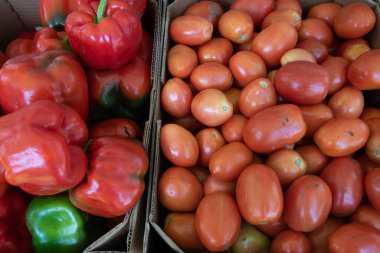 Farmer's Market.  Boxes of red bell peppers and Roma tomatoes.