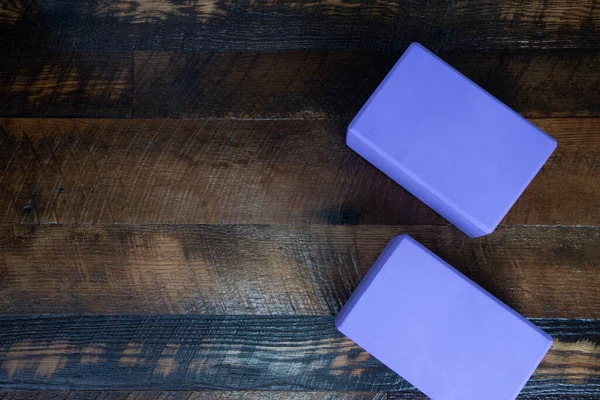 Purple yoga blocks on a wooden floor.  Copy space.