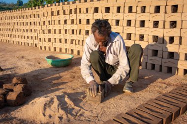 TIKAMGARH, MADHYA PRADESH, INDIA - 11 AĞUSTOS 2021: Kalıplı ve ıslak kilden ev tuğlaları yapan Hintli adam.
