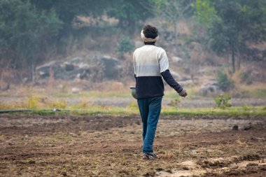 TIKAMGARH, MADHYA PRADESH, Hindistan - 14 Mayıs 2022: Çiftçi tarlada elleriyle buğday tohumu saçıyor.