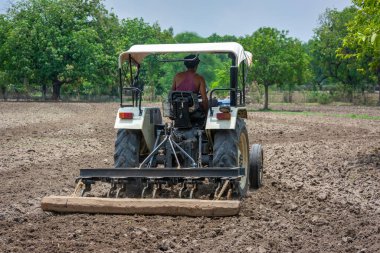 TIKAMGARH, MADHYA PRADESH, Hindistan - 4 Temmuz 2022: Traktördeki çiftçi tarlayı ekime hazırlıyor.
