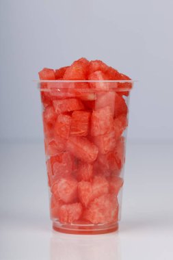 Karpuz dilimleri, beyaz arka planda şeffaf bir bardakta dizilmiş, izole edilmiş.