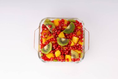 Şeffaf cam bir kasede beyaz arka planda, izole edilmiş kesilmiş meyveler..