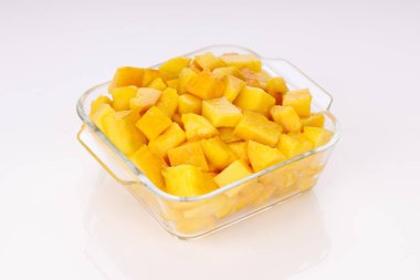 Olgun mango küpleri ya da beyaz arkaplan ile cam kare bir kapta düzenlenmiş parça.