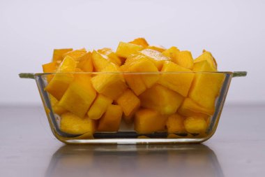 Olgun mango küpleri ya da beyaz arkaplan ile cam kare bir kapta düzenlenmiş parça.