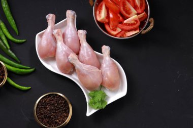 Çiğ tavuk budu ya da bacak parçaları gri arka planlı beyaz masa takımına yerleştirilmiş..