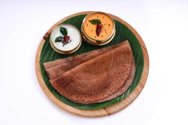 Ragi Dosa, yanında muz yaprağı ve hindistan cevizi turşusuyla kaplı yuvarlak ahşap bir zemine yerleştirilmiş sağlıklı bir Güney Hindistan kahvaltısı..