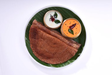 Ragi Dosa, yanında muz yaprağı ve hindistan cevizi turşusuyla kaplı yuvarlak ahşap bir zemine yerleştirilmiş sağlıklı bir Güney Hindistan kahvaltısı..