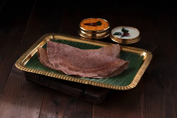Ragi Dosa 南印度人健康的早餐用品 放在一个长方形铜盘上 内衬香蕉叶和放在旁边的椰子栗子 — 图库照片