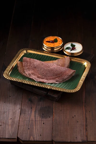 Ragi Dosa 南印度人健康的早餐用品 放在一个长方形铜盘上 内衬香蕉叶和放在旁边的椰子栗子 — 图库照片