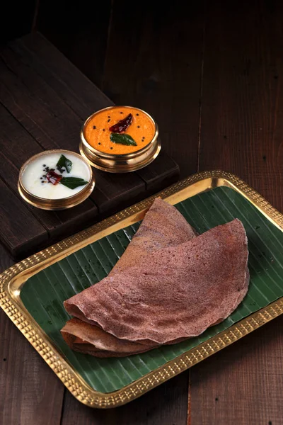 Ragi Dosa 南印度人健康的早餐用品 放在一个长方形铜盘上 内衬香蕉叶和放在旁边的椰子栗子 — 图库照片