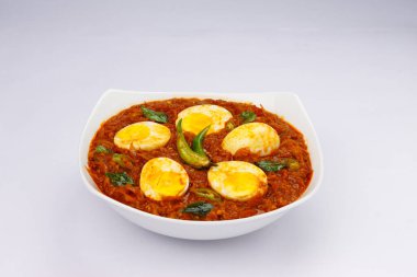 Yumurta rostosu ya da Hint usulü yumurta körisi, baharatlı kırmızı yumurta rostosu beyaz arkaplan ya da desenli seramik bir kasede düzenlenmiş.