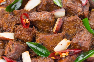 Biftek rosto masala ya da ev yapımı Hint cevizi dilimleri ve beyaz arka planda köri yapraklarıyla süslenmiş ev yapımı köri tarifi. .