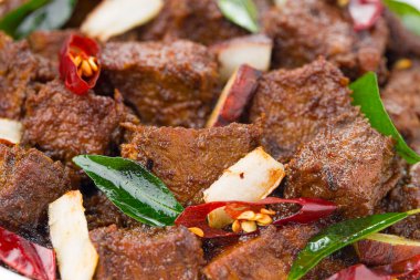 Biftek rosto masala ya da ev yapımı Hint cevizi dilimleri ve beyaz arka planda köri yapraklarıyla süslenmiş ev yapımı köri tarifi. .