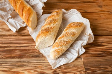 Ekmek ekmeği üzerine susam serpiştirilmiş Tahta masa üzerinde ambalaj kağıdı