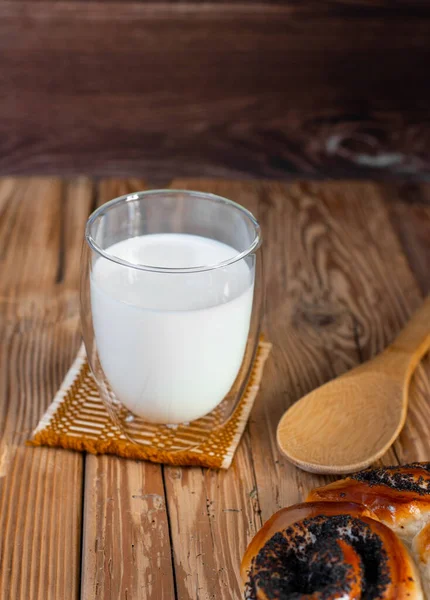 Bir bardak soğuk sütlü kaşık ve kırsal bir masada haşhaşlı çörek.