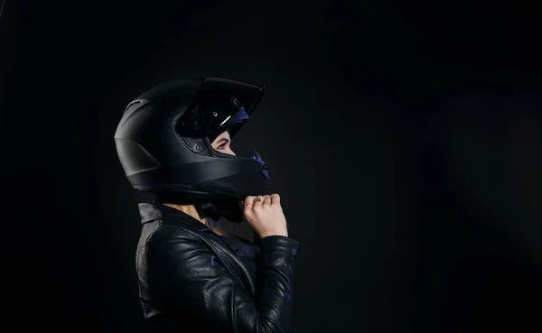 Motosiklet kasklı ve deri ceketli bir kız. Stüdyoda koyu bir arka planda izole edilmiş..