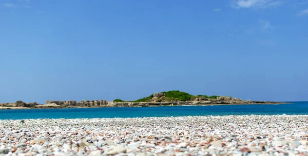 Taşlı deniz kıyısı ve mavi gökyüzü.