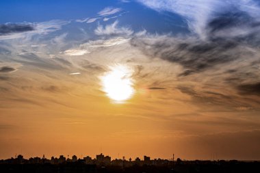Ufuktaki şehrin ufuk çizgisi ve alacakaranlıkta güneş ceviz ağaçlarının arkasından iniyor..