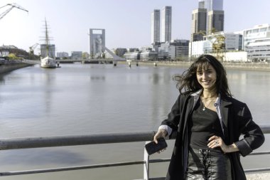 Güneşli bir günde limanda akıllı telefon kullanan genç bir kadının portresi.