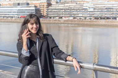 Güneşli bir günde limanda akıllı telefon kullanan genç bir kadın. Boşluğu kopyala