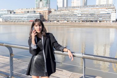 Güneşli bir günde limanda akıllı telefon kullanan genç bir kadın. Boşluğu kopyala
