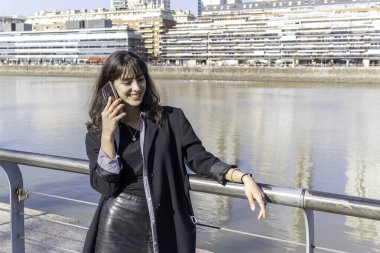 Güneşli bir günde limanda akıllı telefon kullanan genç bir kadın. Boşluğu kopyala