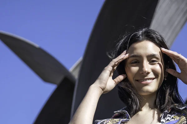 portrait of a young woman with black hair smiling in the street