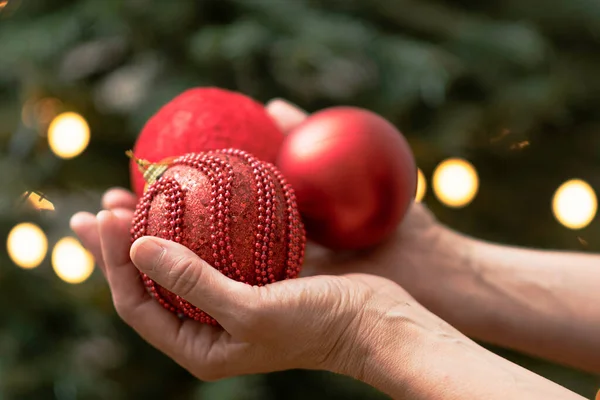 hands holding red balls to hang on a Christmas tree