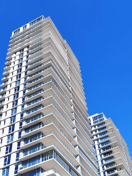 İki modern yüksek katlı apartman, açık mavi gökyüzüne karşı, aşağıdan manzara..