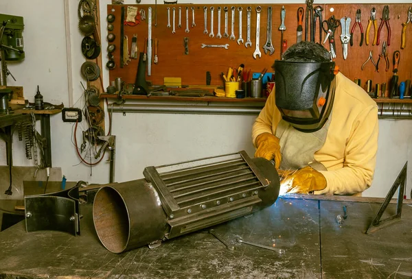 Koruyucu maskeli bir kaynakçı atölyesinde metal bir parça buldu.
